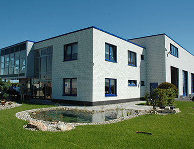 Außenansicht des neuen Bürogebäudes der Stork Umwelt GmbH mit Grünfläche und Teich